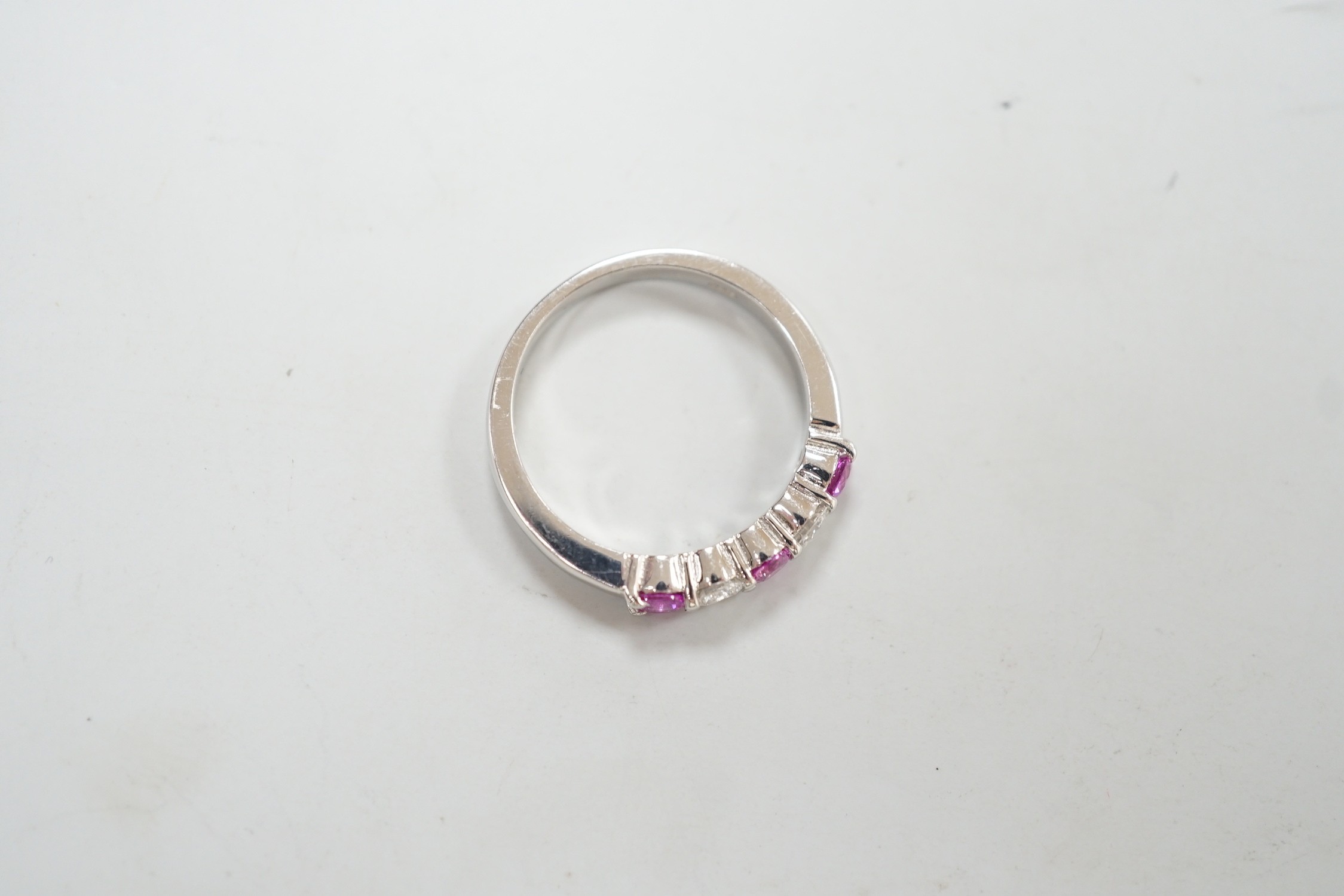 A modern 18ct white gold, three pink stone and two stone diamond set half hoop ring, size M, gross weight 4 grams.